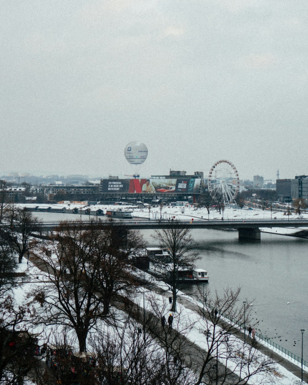 a view of a river and a bridge with a ferris wheel in the distance
