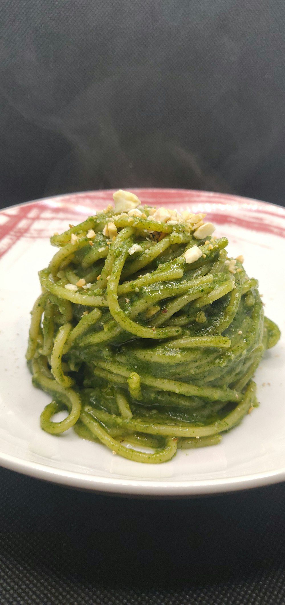 a white plate topped with green pasta covered in pesto