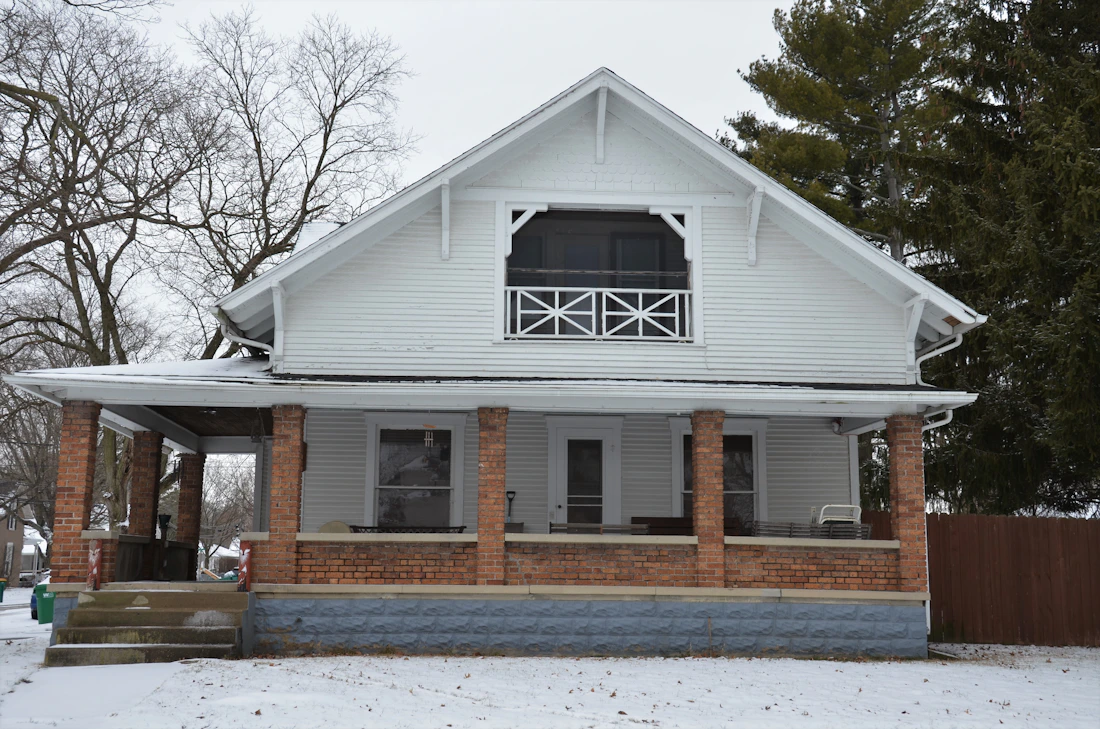 Classic white two-storey American farmhouse with brick porch