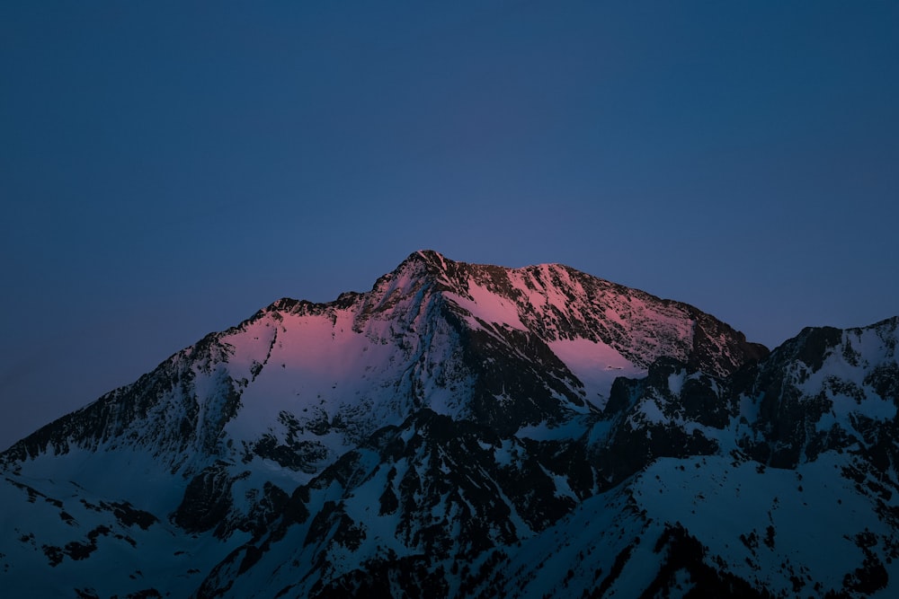 a snow covered mountain with a pink light on it
