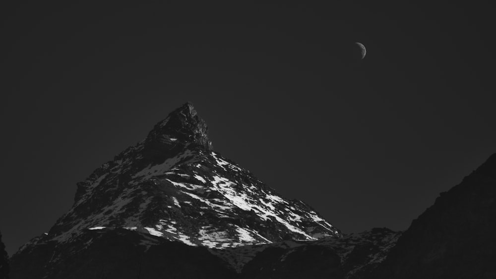 a very tall mountain with a moon in the sky