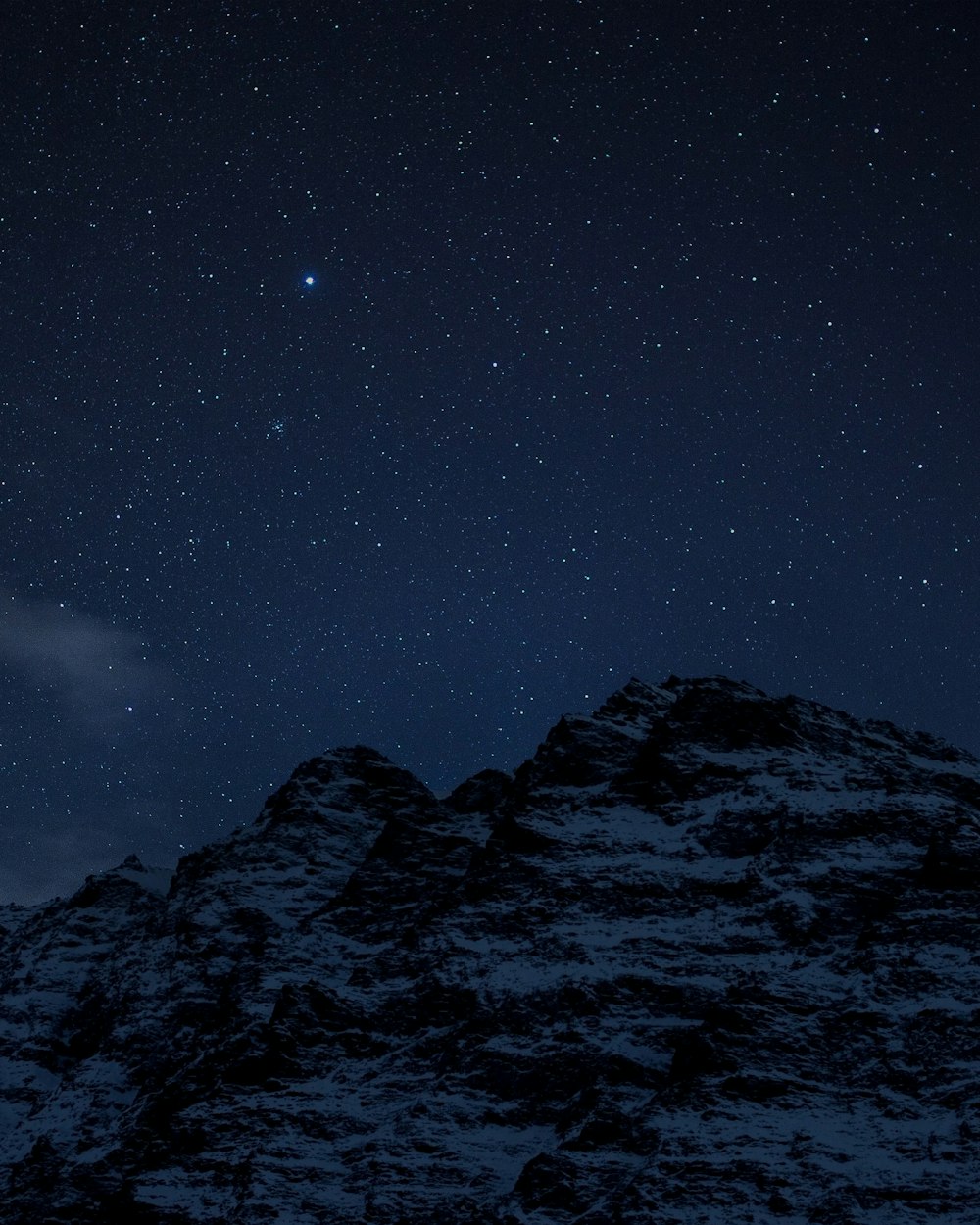 El cielo nocturno con estrellas sobre una montaña
