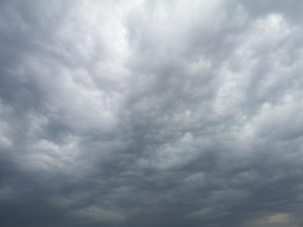 a group of people standing on top of a beach under a cloudy sky