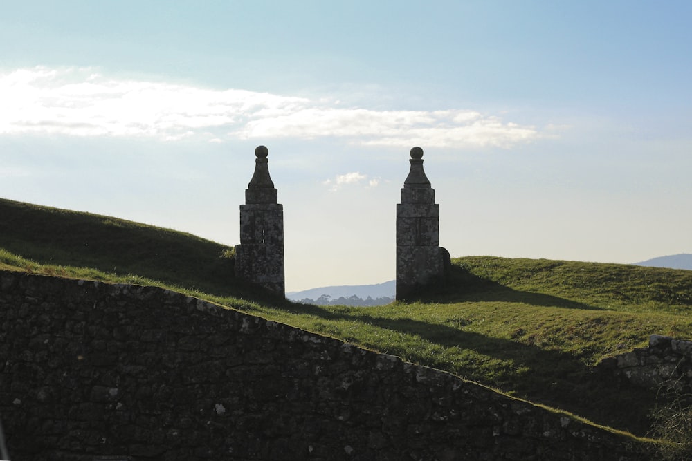 a couple of stone towers sitting on top of a lush green hillside