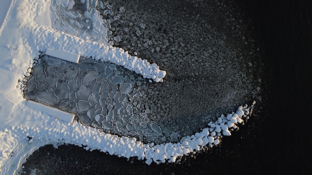 an aerial view of snow covered rocks and water