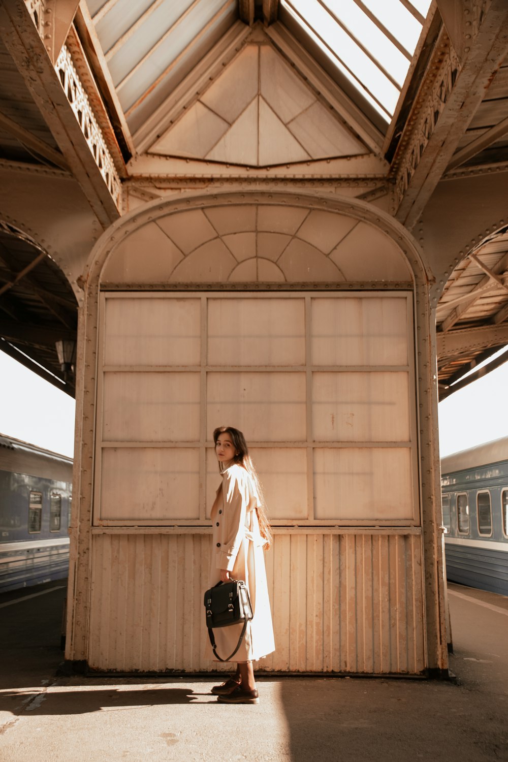 a woman standing in a train station with a suitcase