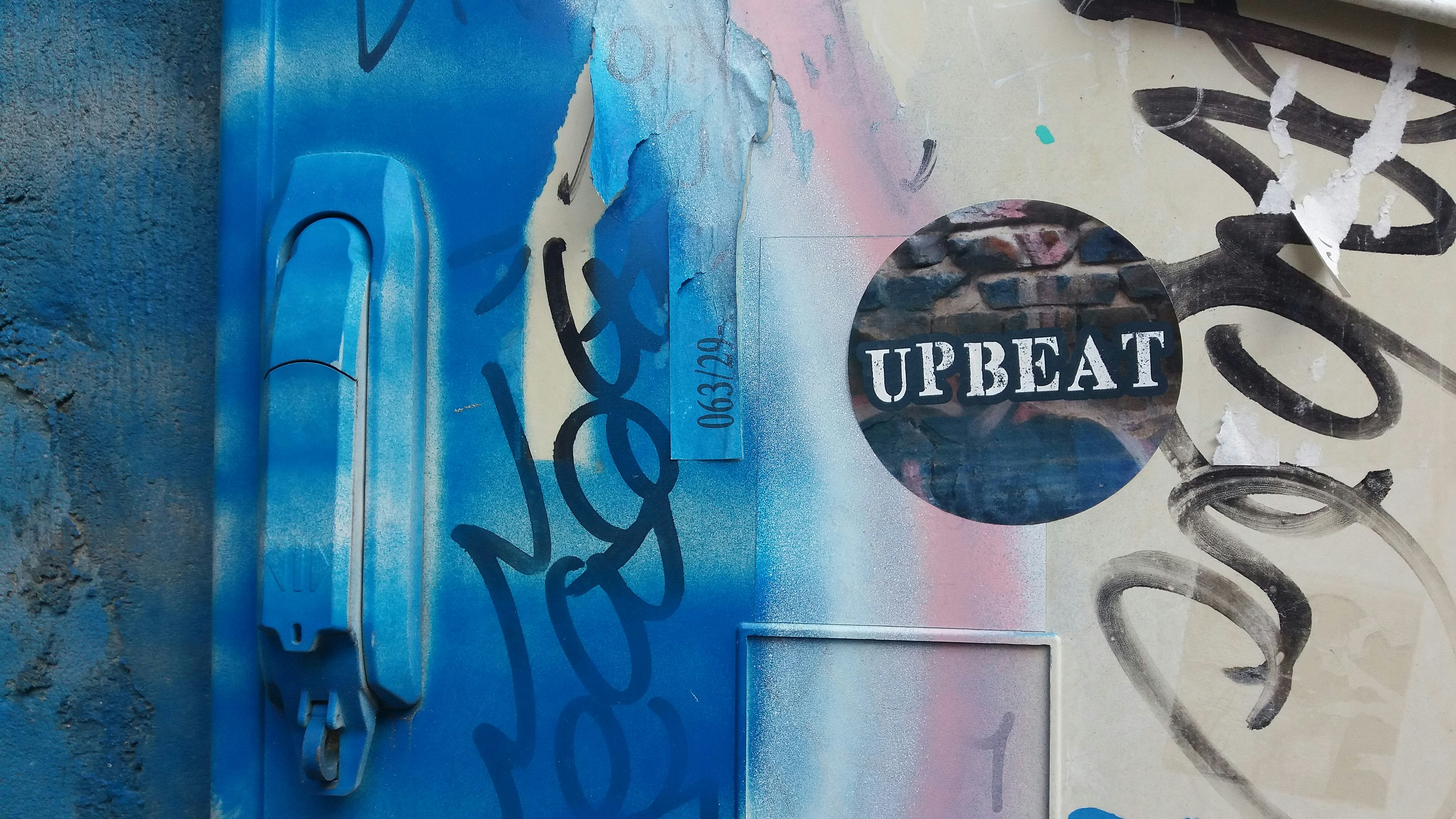 graffiti on the side of a building with the word upbeat painted on it