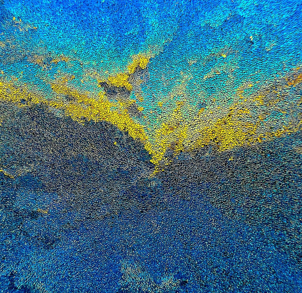 a blue and yellow background with some yellow paint