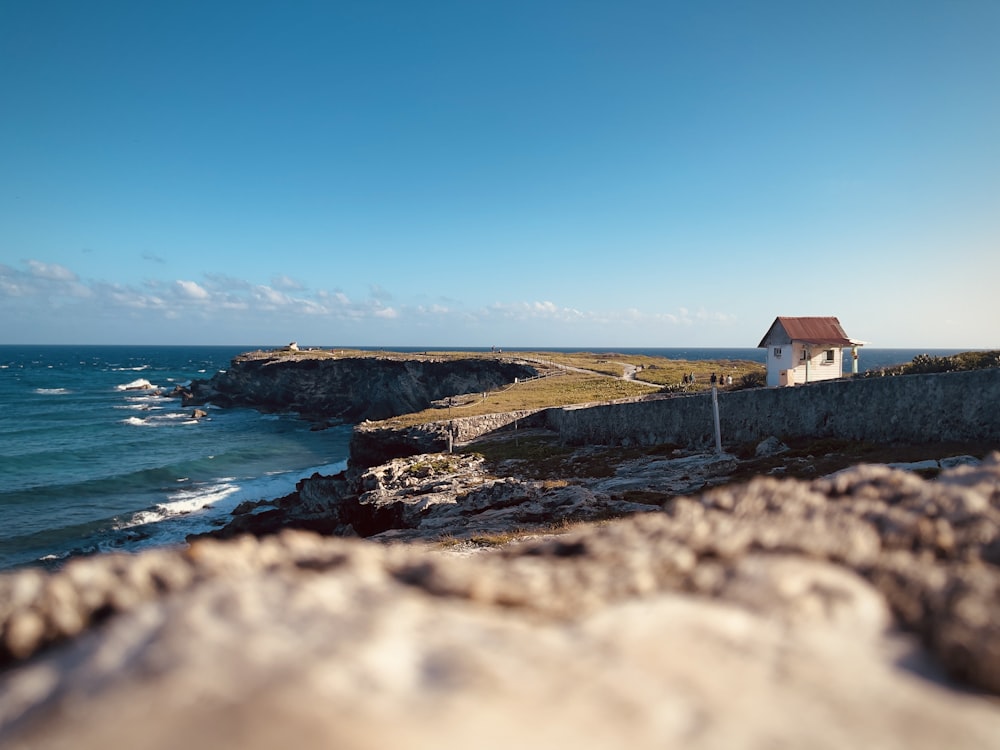 a white house sitting on top of a cliff next to the ocean