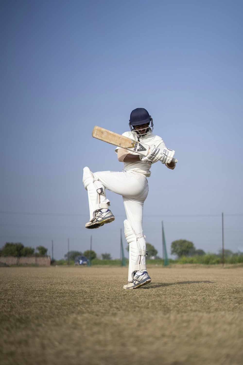 a man in a white uniform playing a game of cricket