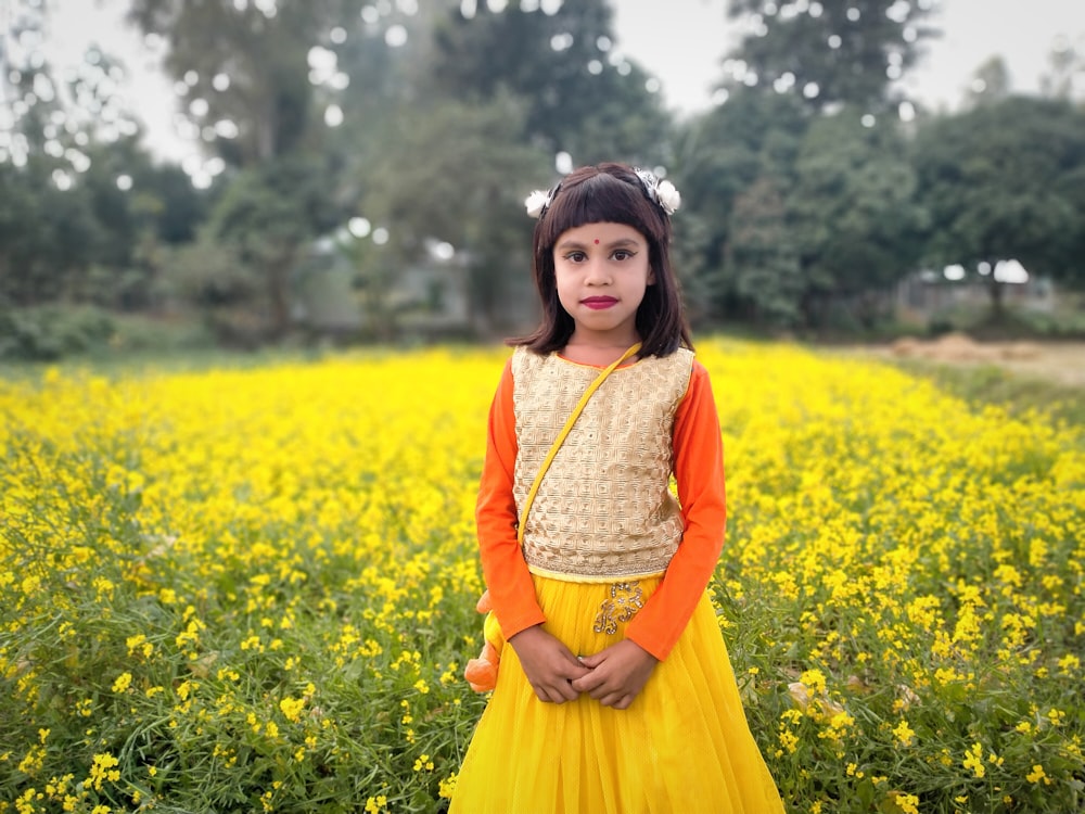Ein kleines Mädchen steht in einem Feld mit gelben Blumen