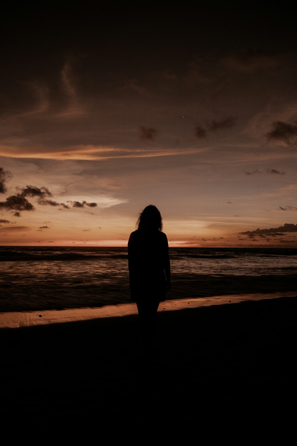 a person standing on a beach at sunset