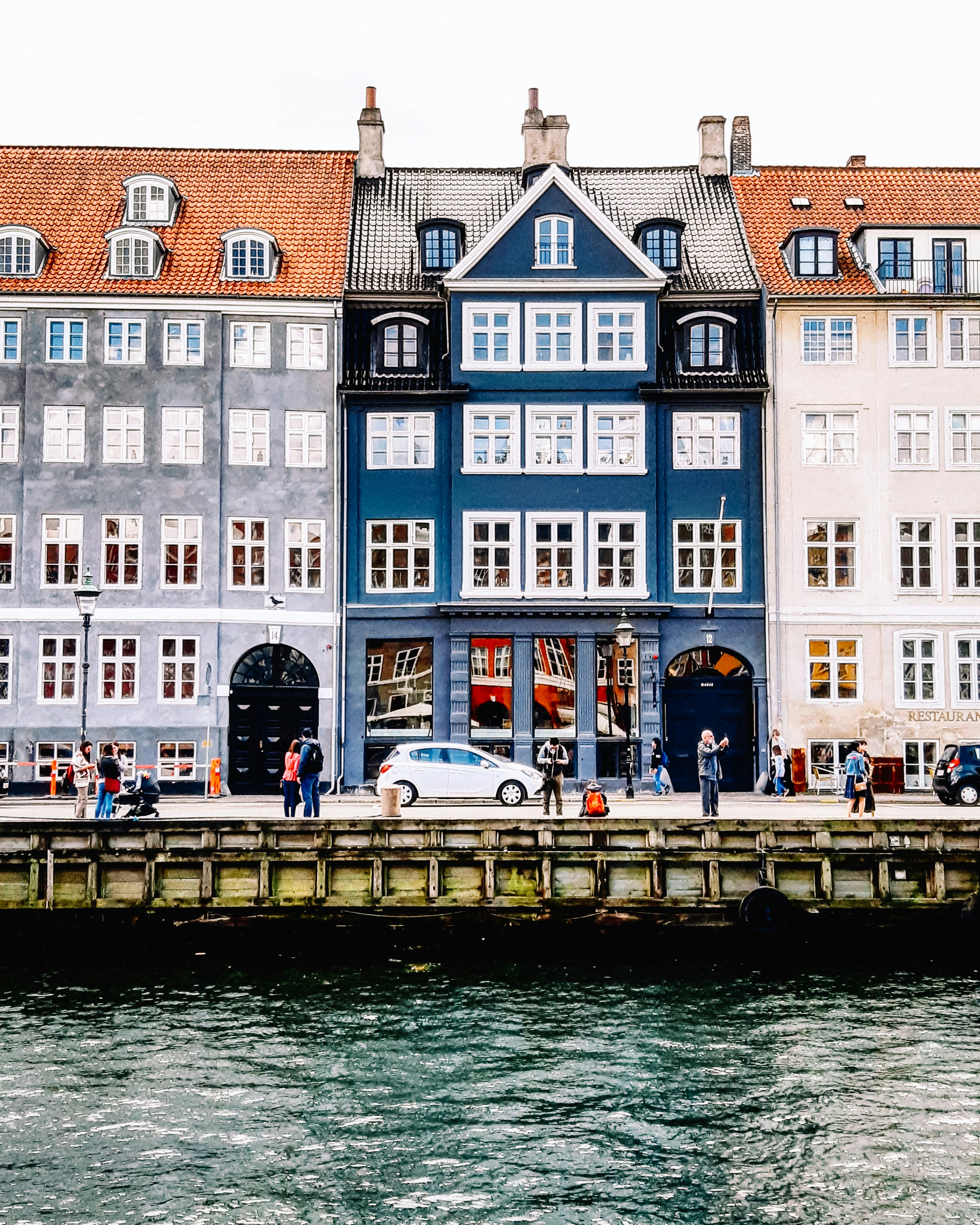 a group of people standing outside of a building next to a body of water