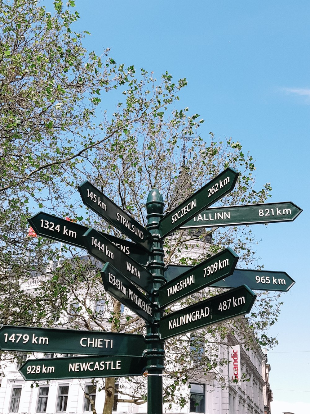 a pole with many signs on it in front of a building