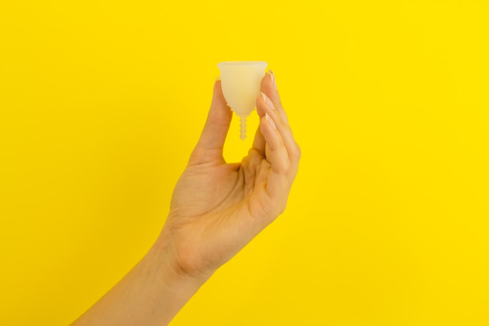 una mano che tiene un pezzo di cibo su uno sfondo giallo