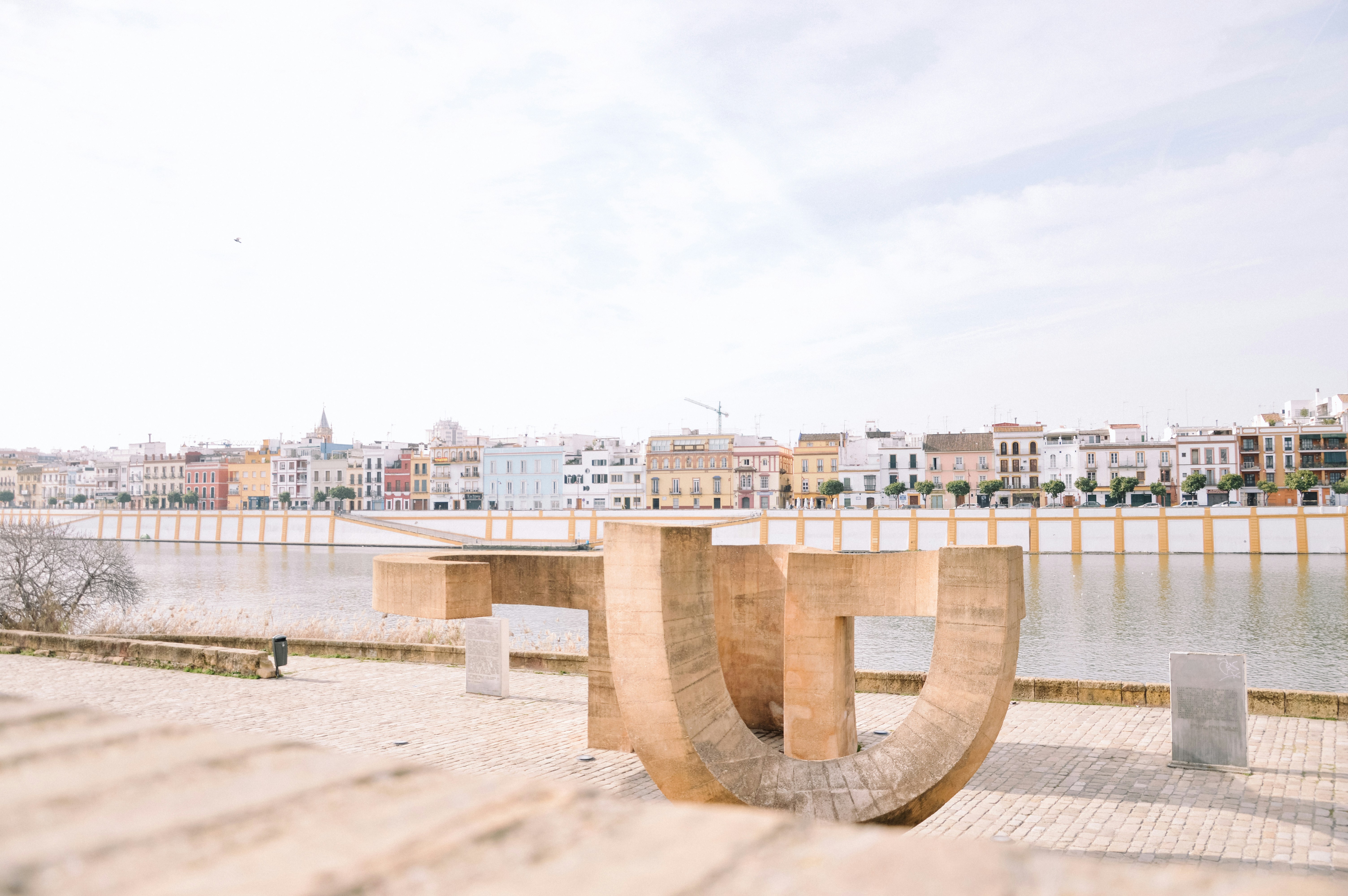 A wooden bench sitting next to a body of water photo – Free Water Image ...