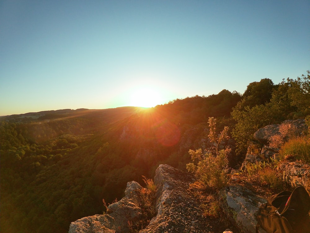 the sun is setting over a rocky cliff