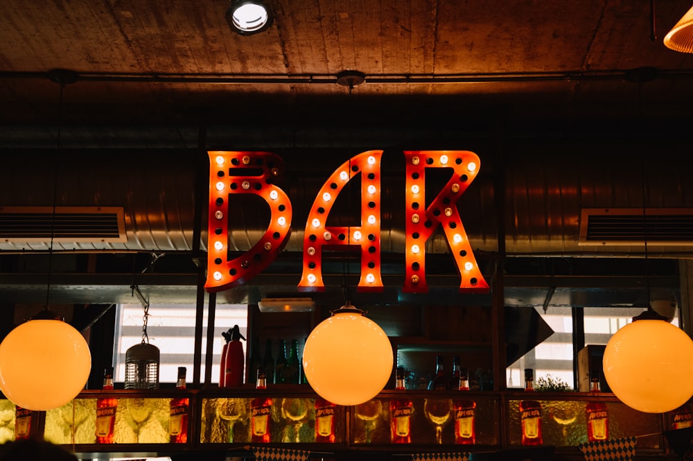 a lighted bar sign above a bar filled with balloons