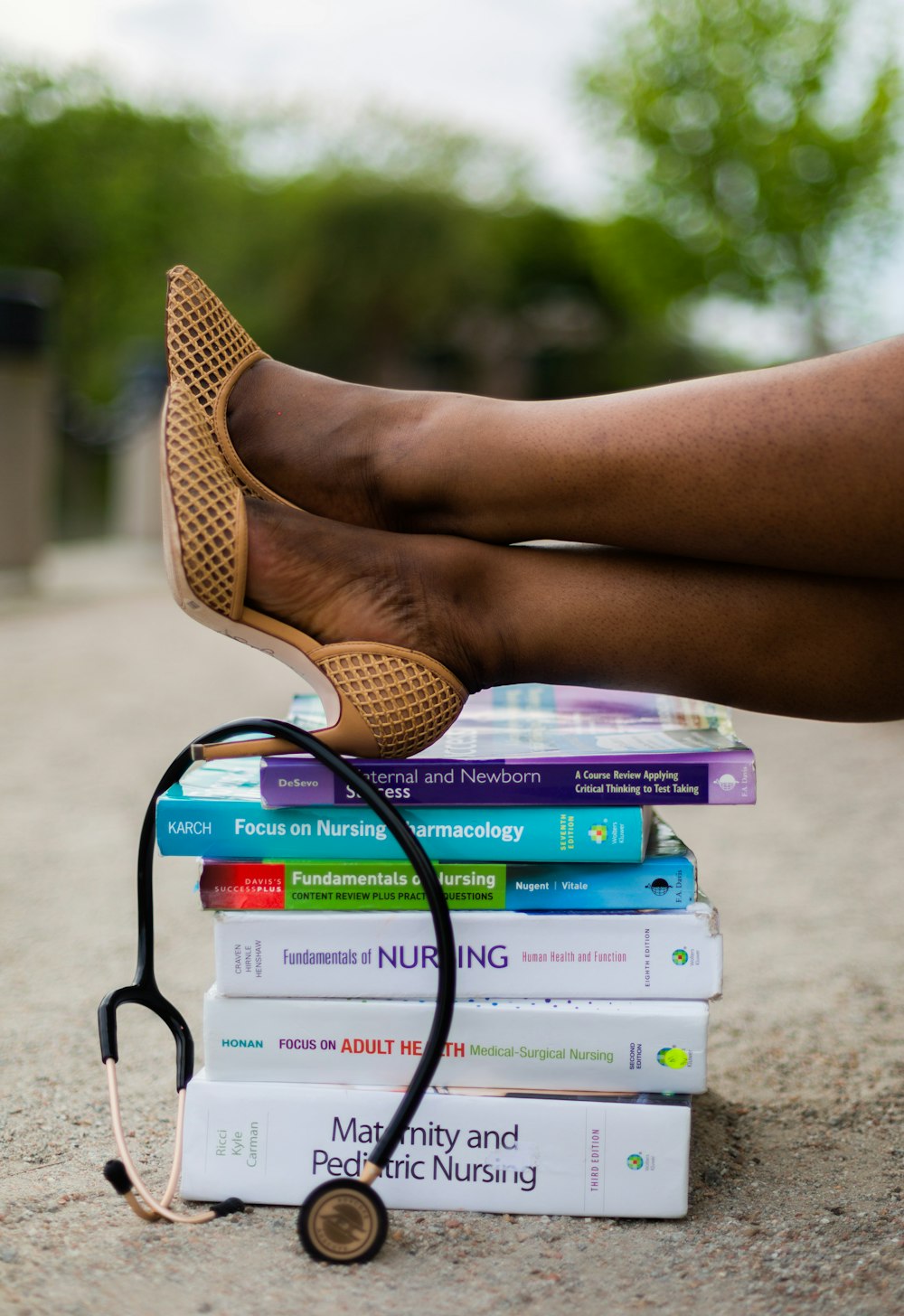 los pies de una mujer en una pila de libros con un estetoscopio