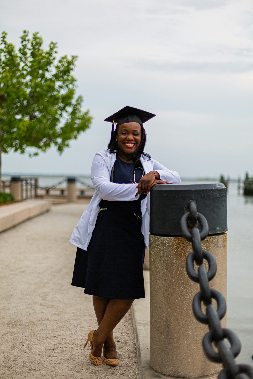 a woman in a graduation gown leaning against a chain