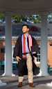 a man in a graduation gown standing under a gazebo