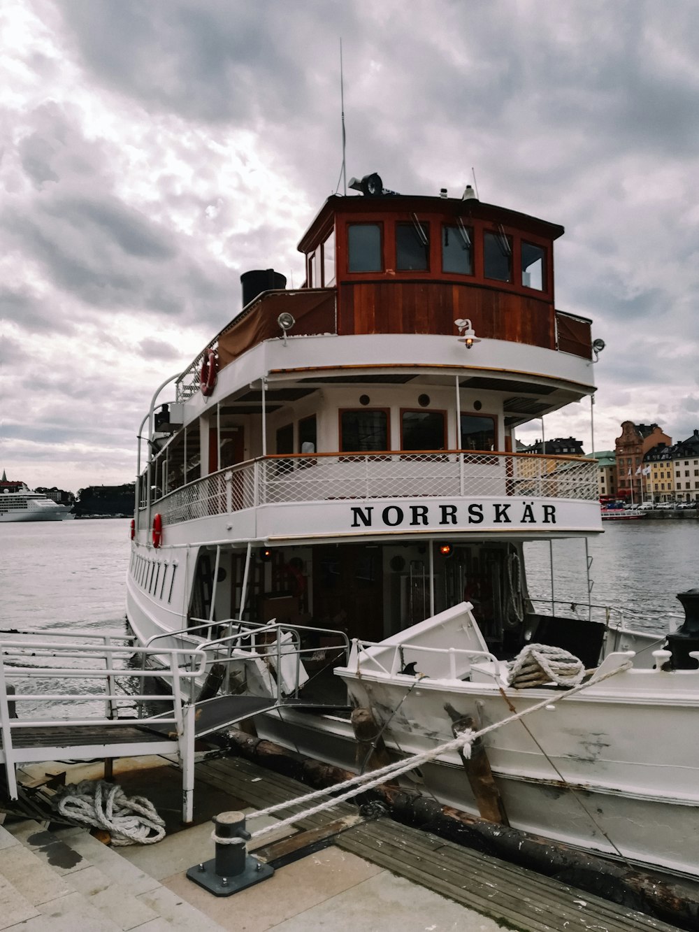 a boat docked at a pier with a cloudy sky in the background