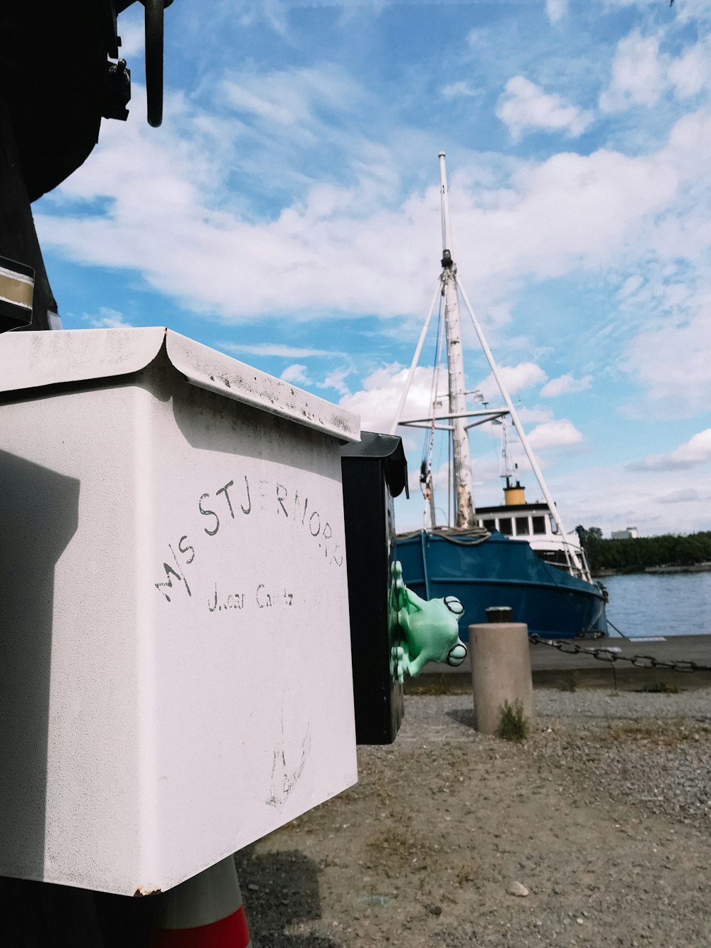 a truck parked next to a body of water with a boat in the background