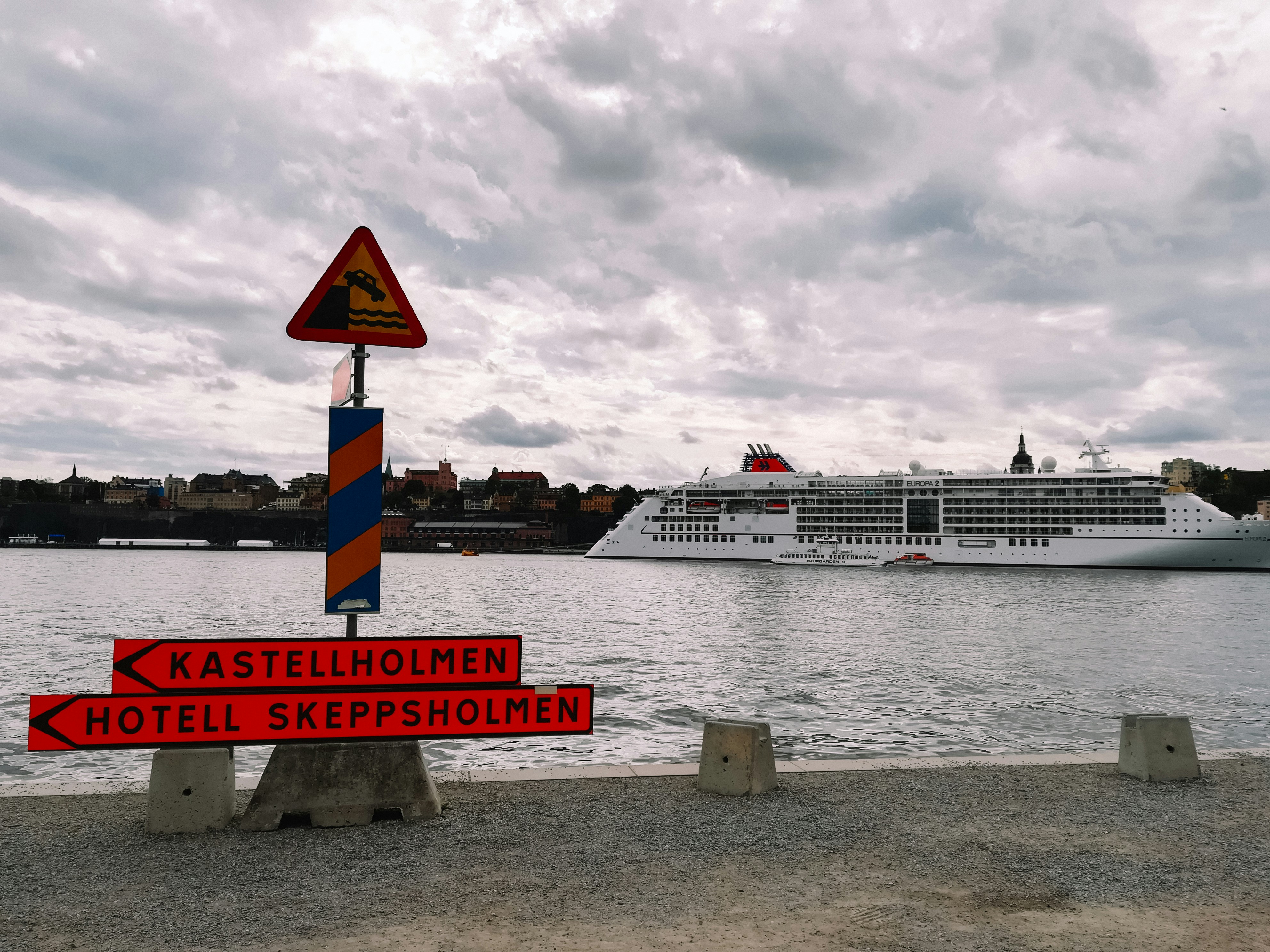 a cruise ship is in the background and a sign is in the foreground