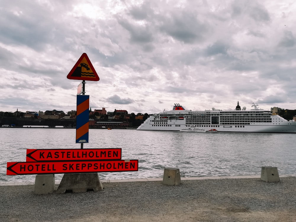 a cruise ship is in the background and a sign is in the foreground