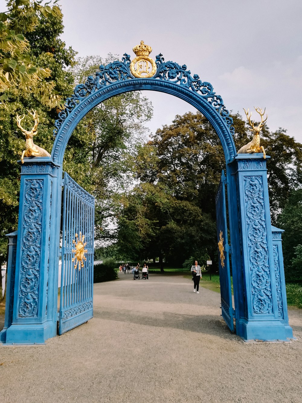 a blue gate with two golden statues on top of it