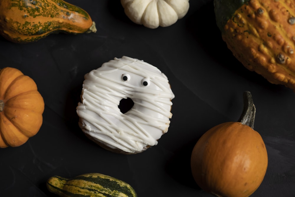 une surface noire avec des citrouilles, des courges et un beignet