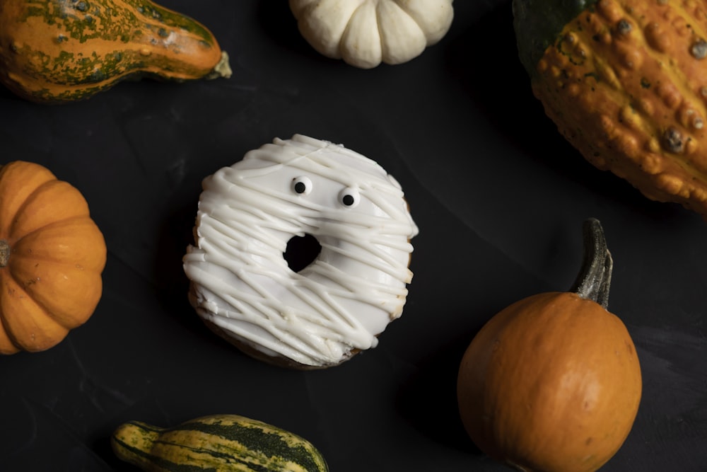 a black surface with pumpkins, gourds, and a doughnut