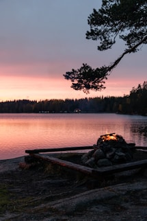 a fire pit on the shore of a lake