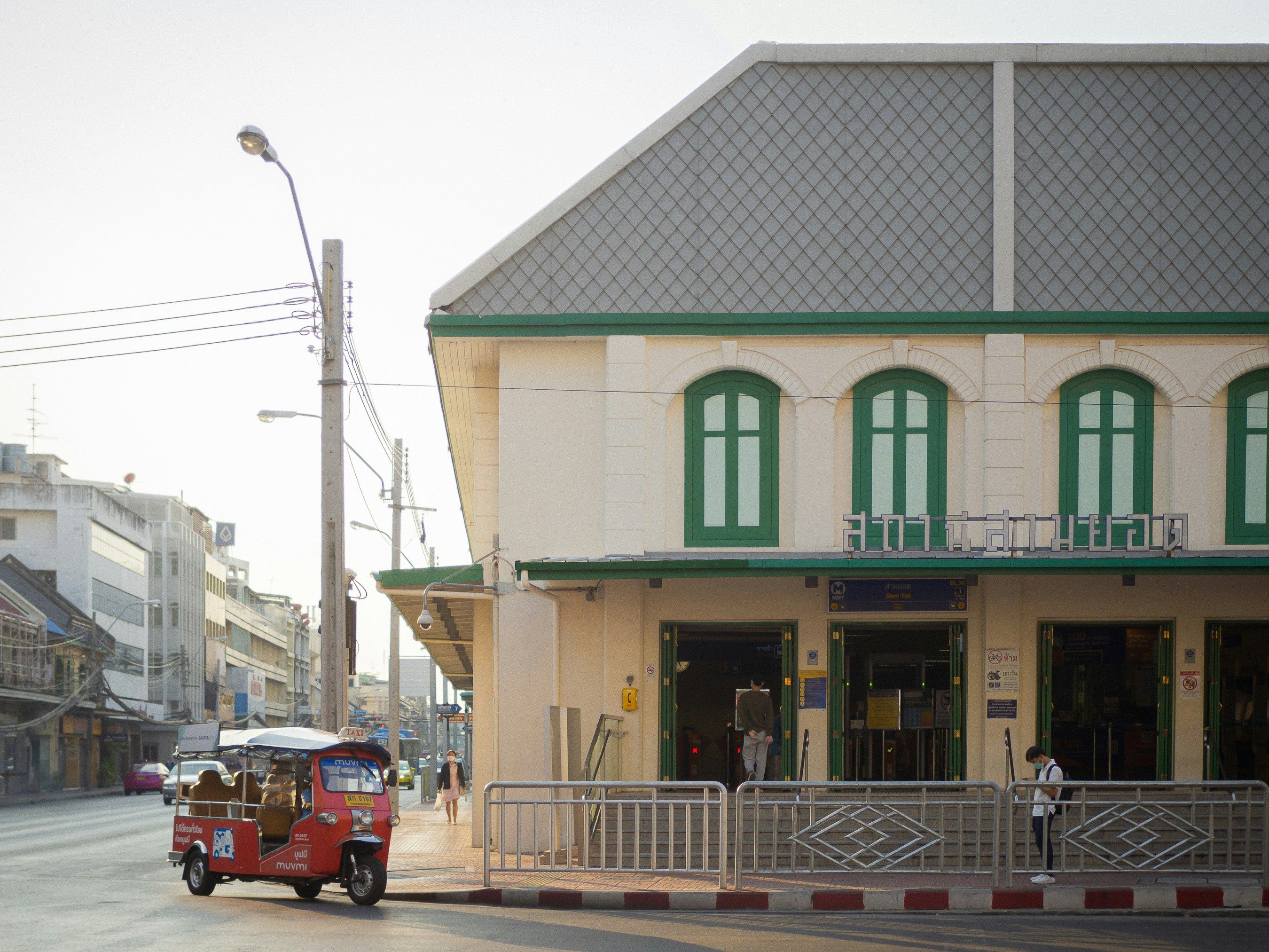 a red car driving down a street next to a tall building