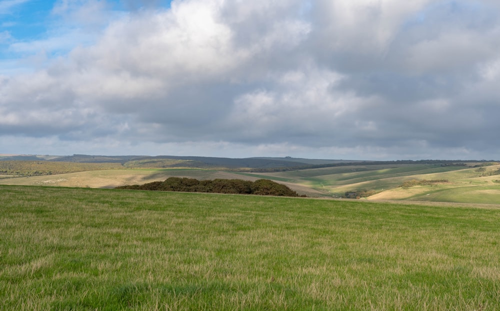 a grassy field with rolling hills in the distance