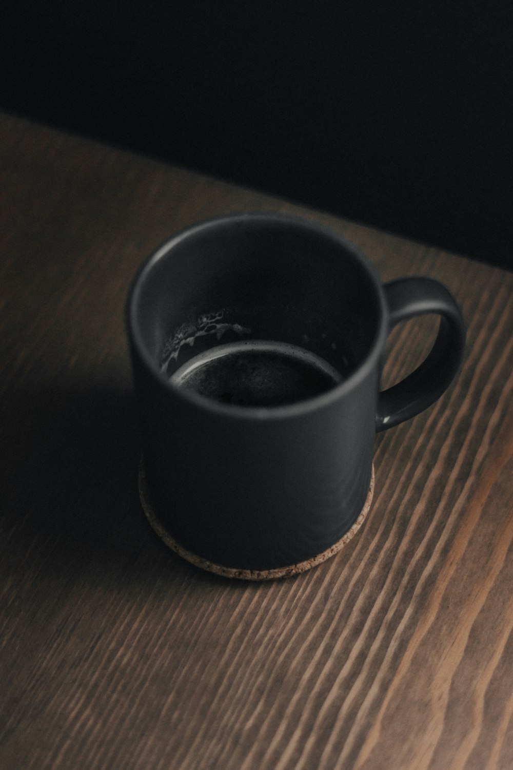 a black cup sitting on top of a wooden table