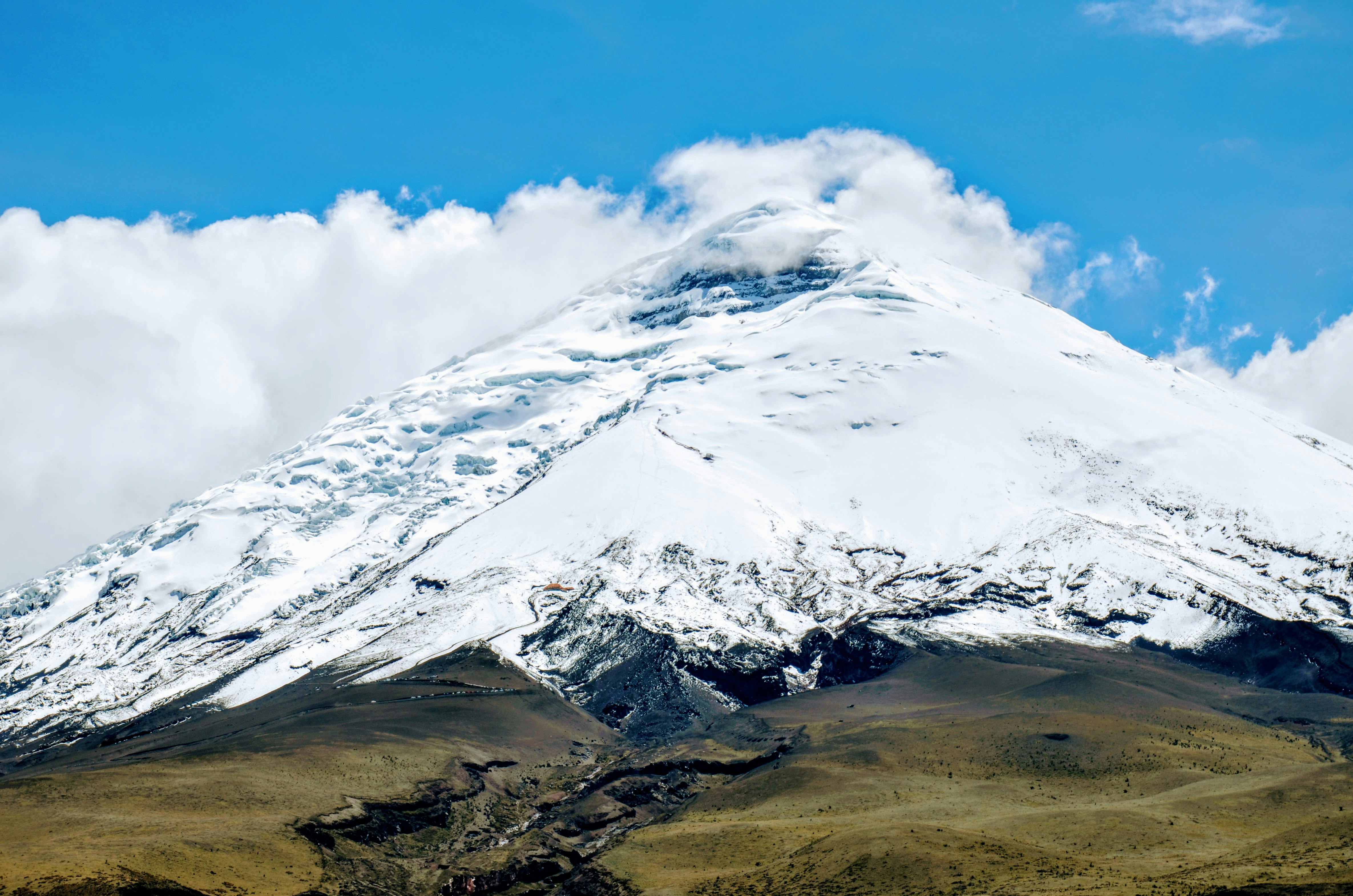 a large mountain covered in snow under a blue sky