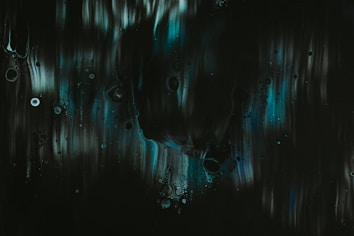 Dark abstract artwork featuring fluid, flowing patterns with subtle circular elements. Shades of deep green, black, and hints of teal or blue create a mysterious ambiance.