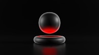 A metallic sphere with a gradient of red and black hovers above a matching circular metallic ring. Both objects are set against a dark background, emphasizing the sleek and minimalistic design.