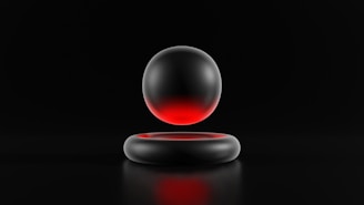 A metallic sphere with a gradient of red and black hovers above a matching circular metallic ring. Both objects are set against a dark background, emphasizing the sleek and minimalistic design.