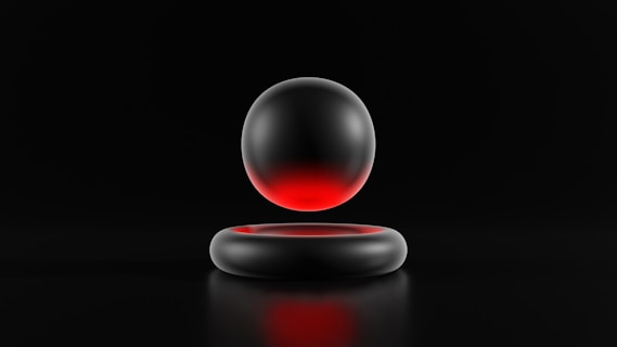 A metallic sphere with a gradient of red and black hovers above a matching circular metallic ring. Both objects are set against a dark background, emphasizing the sleek and minimalistic design.