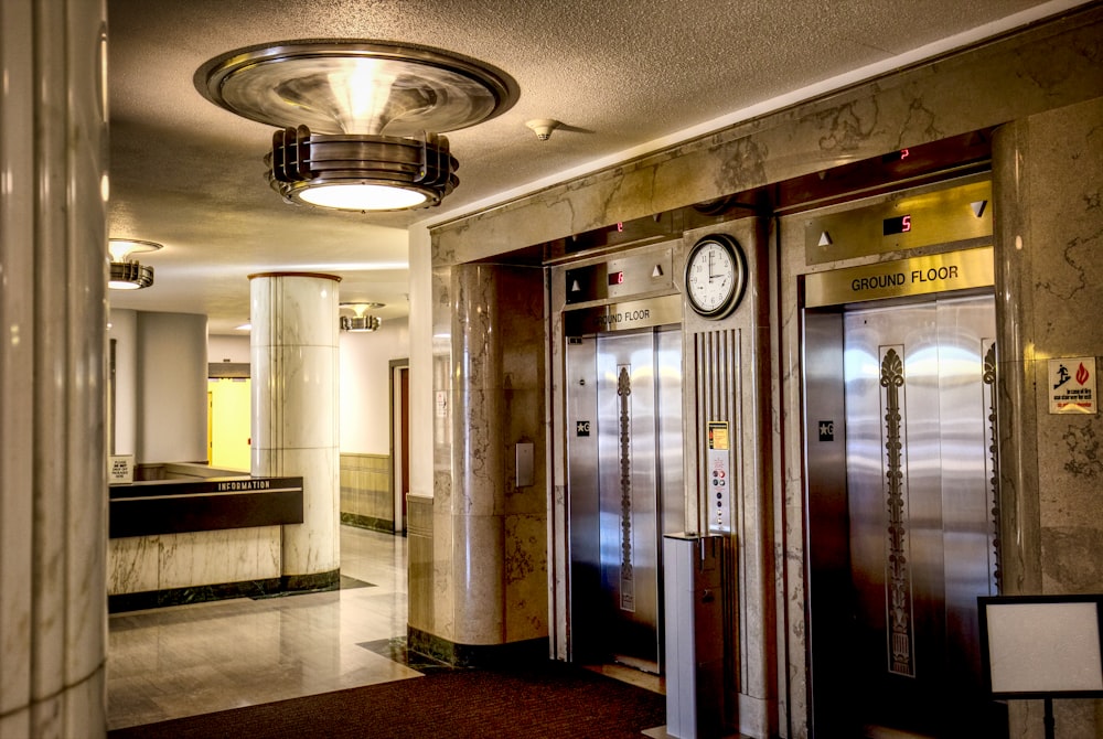 a hotel lobby with two elevators and a clock on the wall