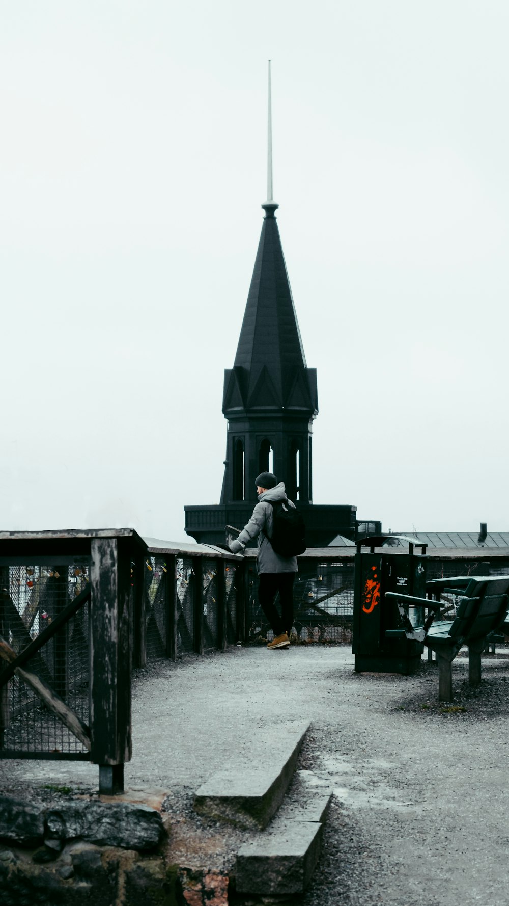 Una persona parada en un puente con una torre del reloj en el fondo