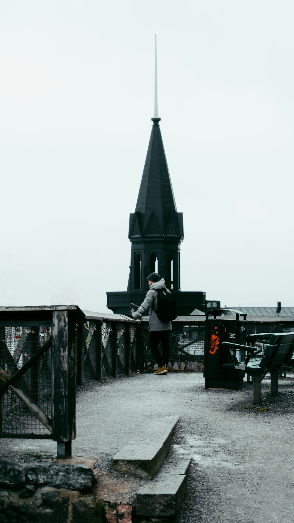 a person standing on a bridge with a clock tower in the background