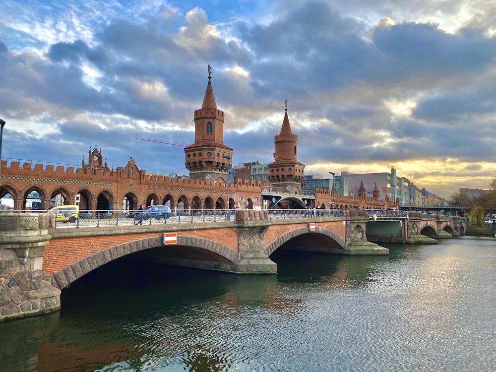 a bridge over a body of water with a clock tower in the background