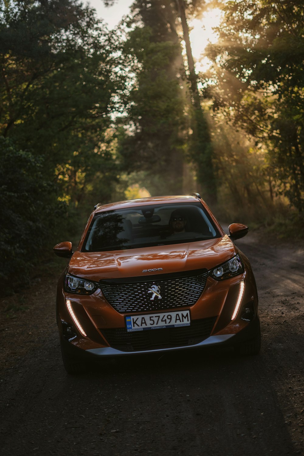 an orange car driving down a dirt road