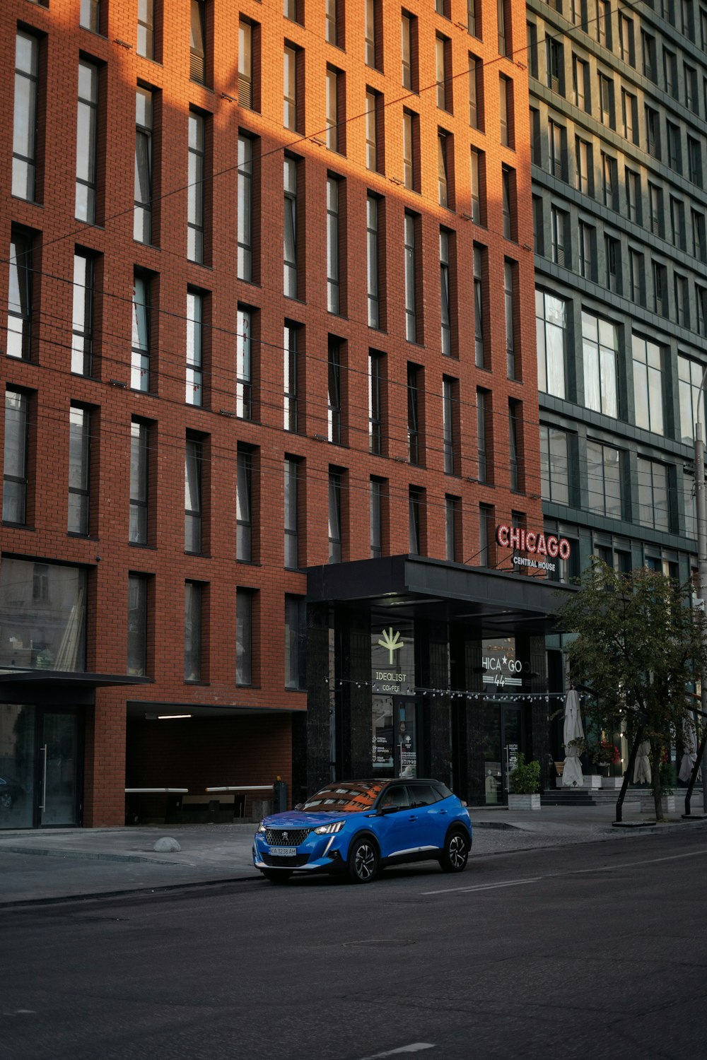 a blue car parked in front of a tall building