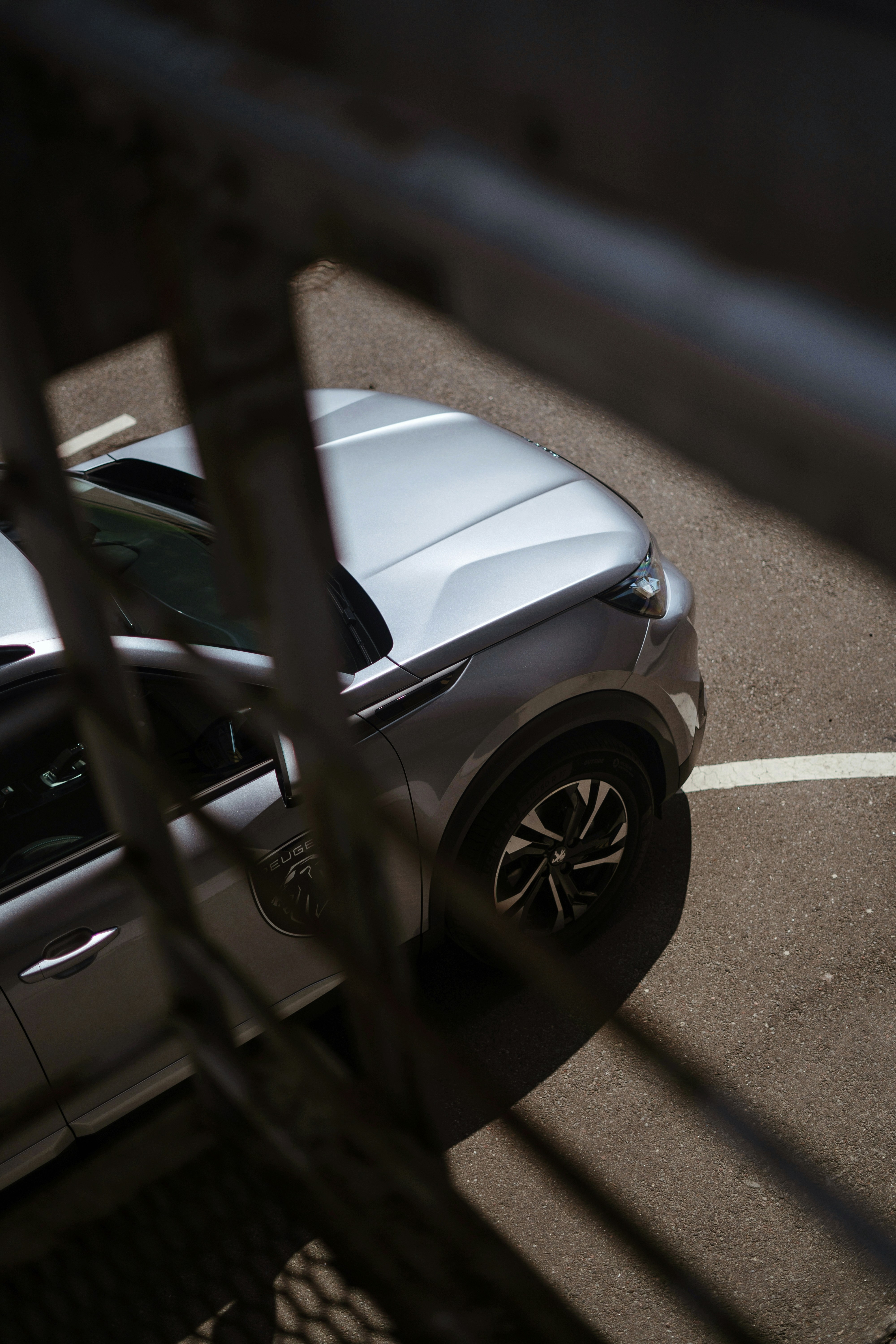 ein Auto, das auf einem Parkplatz neben einem Zaun geparkt ist