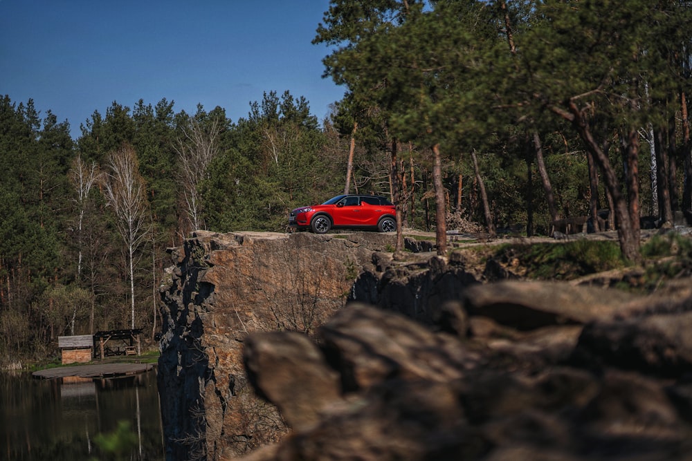 Une voiture rouge garée au sommet d’une falaise