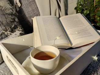 A peaceful desk with an open book, soft lighting, and a cup of tea nearby.